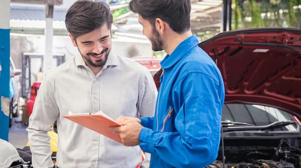 Aviseur technique présentant un rapport d'expertise à un client dans un garage